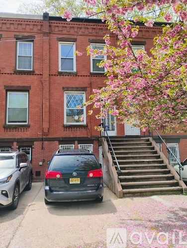 A black car is parked in front of a red brick building.