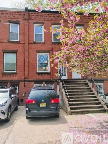 A black car is parked in front of a red brick building.
