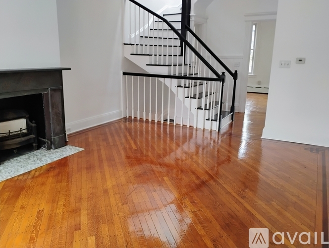 A wooden floor with a fireplace and a staircase.