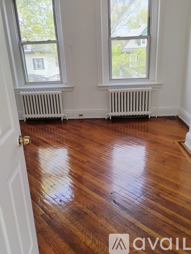 A room with wooden floors and two windows.