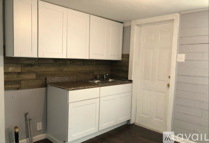 A kitchen with white cabinets and a white door.