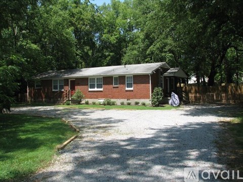 A house with a gravel driveway and a fence in the front yard.