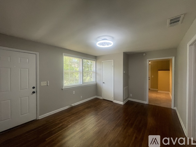 A spacious room with wooden floors and a large window.