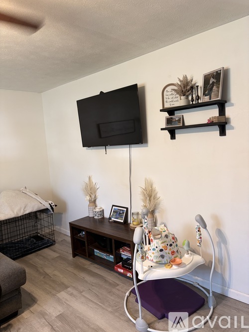 A living room with a television, a chair, and a shelf with decorative items.