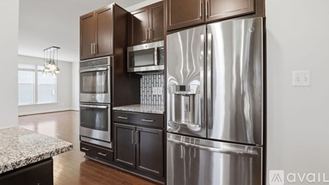 A modern kitchen with a stainless steel refrigerator and dark brown cabinets.