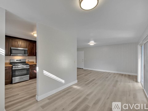 A spacious, empty room with wooden flooring and white walls.