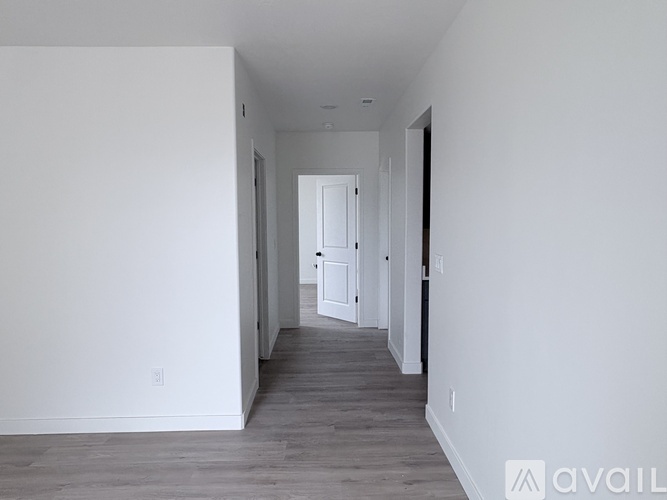 A long, empty hallway with white walls and a wooden floor.