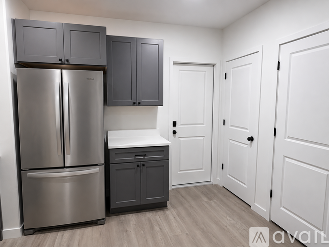 A kitchen with a stainless steel refrigerator and cabinets.