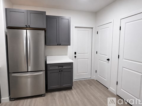 A kitchen with a stainless steel refrigerator and cabinets.
