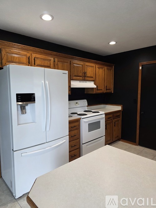 A white refrigerator is in a kitchen with wooden cabinets.