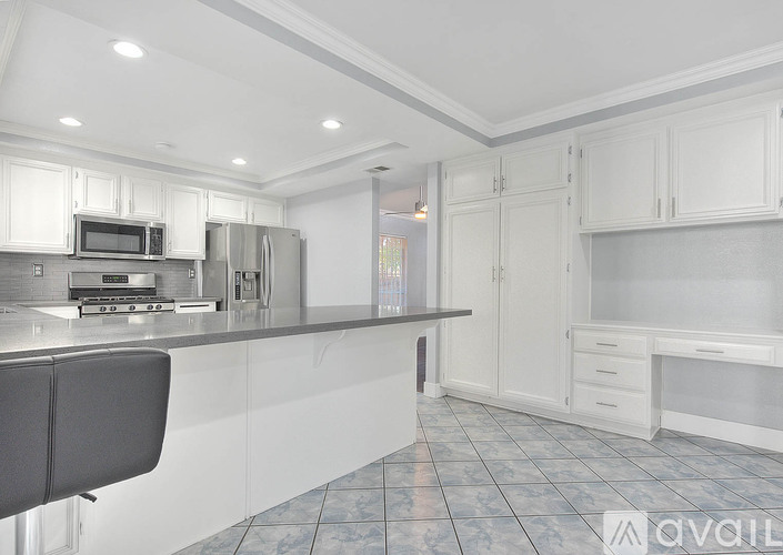 A kitchen with white cabinets and a black chair.