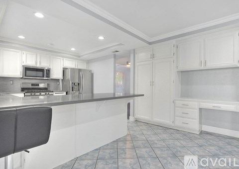A kitchen with white cabinets and a black chair.