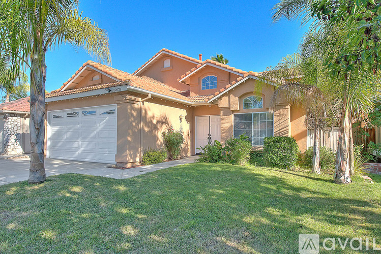 A house with a white garage door and a brown roof is for sale.