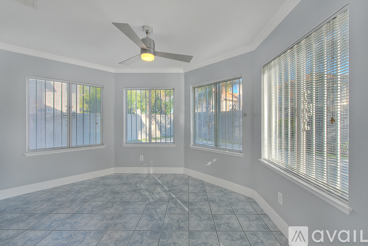 A room with a ceiling fan and three windows.