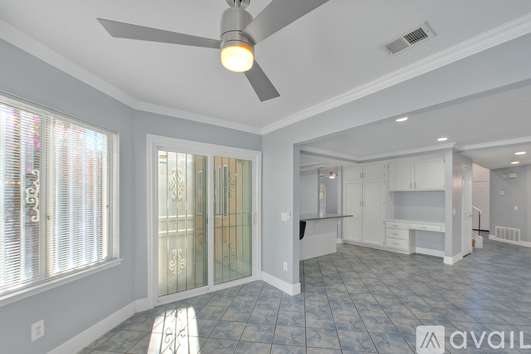 A spacious room with a ceiling fan and tiled flooring.