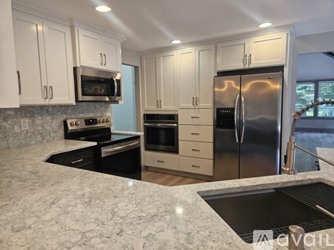 A kitchen with white cabinets and a marble countertop.