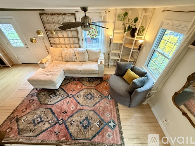 A living room with a rug, a sofa, and a fan.