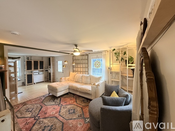 A living room with a rug, a couch, and a chair.