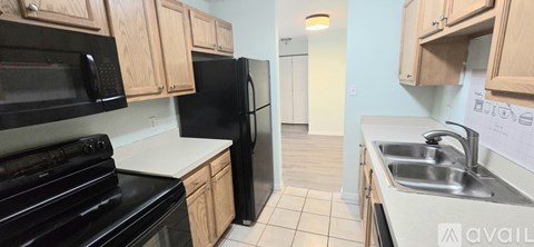 A kitchen with black appliances and wooden cabinets.