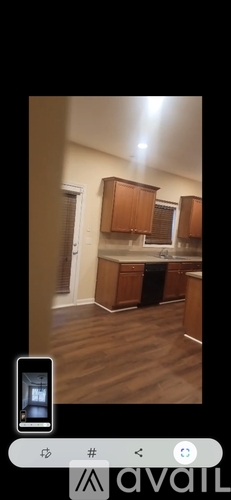 A kitchen with wooden cabinets and a phone displaying the same image.