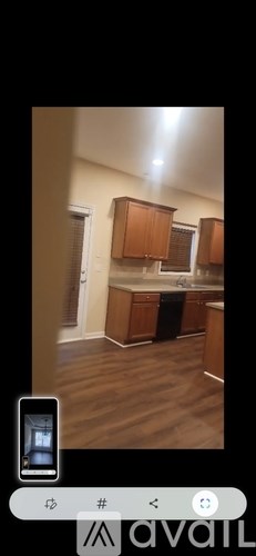A kitchen with wooden cabinets and a phone displaying the same image.