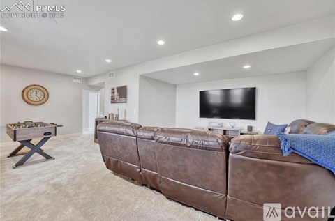 A living room with a brown leather couch and a flat screen TV mounted on the wall.