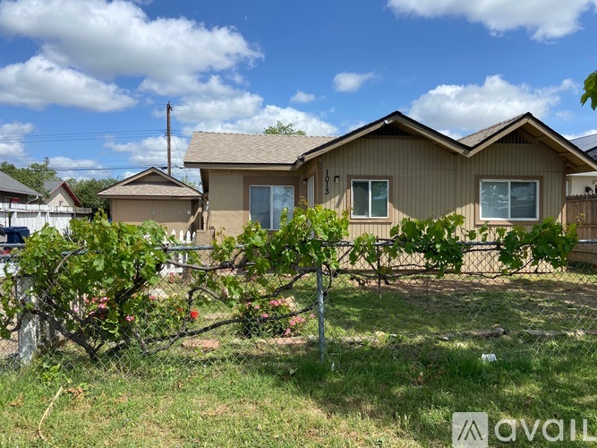 A house with a brown roof and a fence in front of it.