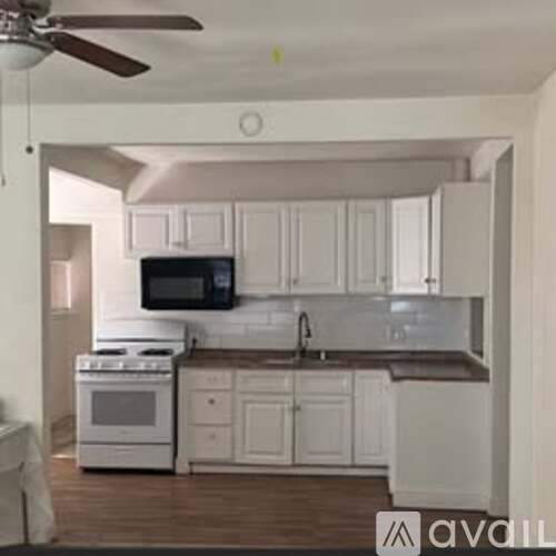 A kitchen with white cabinets and a black microwave.