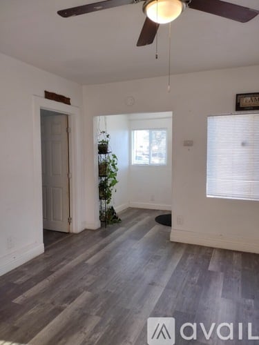 A room with a ceiling fan and wooden flooring.