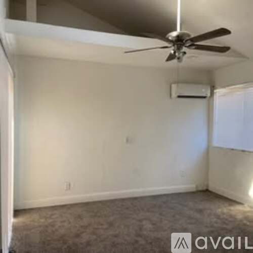 A room with a ceiling fan and an air conditioner unit mounted on the wall.