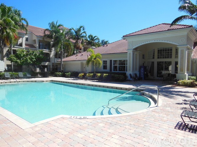 A pool in front of a house with a patio and palm trees.