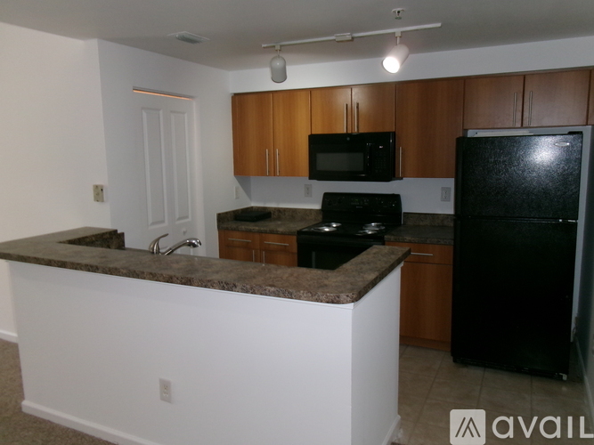 A kitchen with black appliances and brown cabinets.