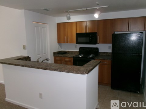 A kitchen with black appliances and brown cabinets.