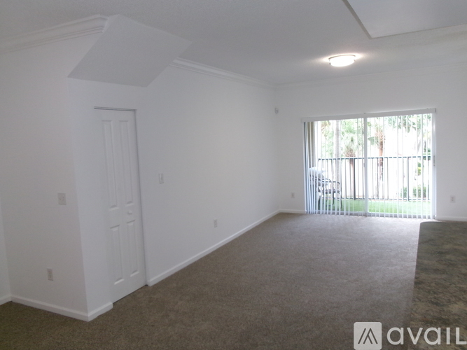 A spacious room with a carpeted floor and a sliding glass door leading to a balcony.
