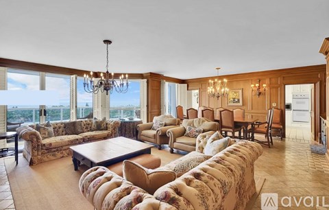 A living room with a large sectional sofa and a chandelier.