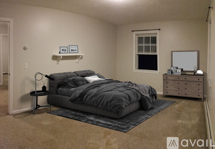 A bedroom with a bed, nightstand, and a window.