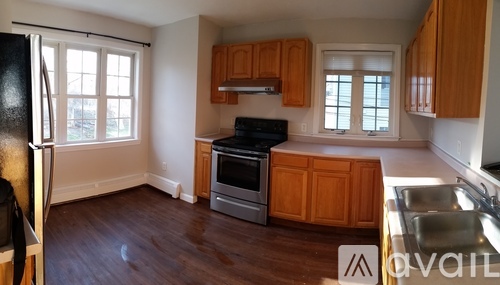 A kitchen with wooden cabinets and a black fridge.