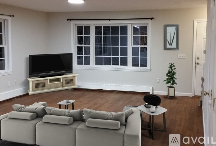 A living room with a grey couch, a television, and a plant.