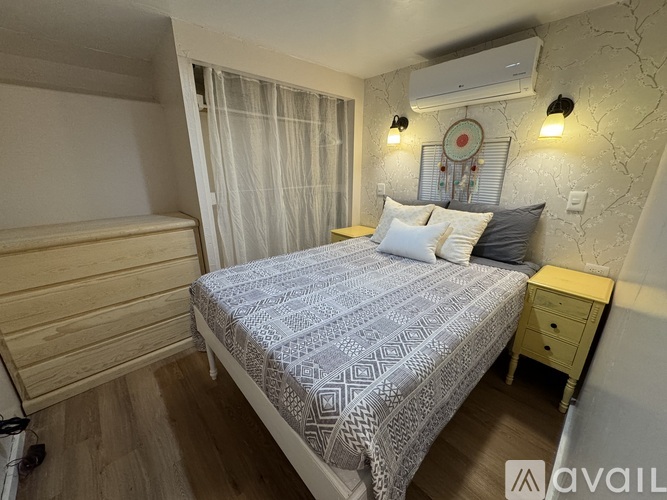 A bedroom with a bed, nightstand, and a wall-mounted air conditioner unit.