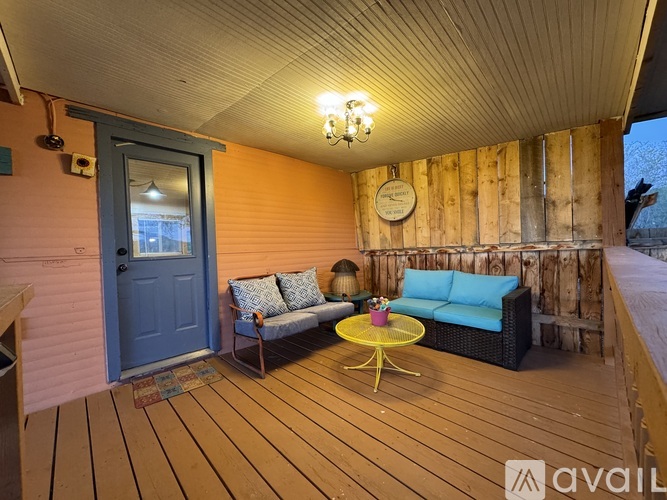 A wooden deck with a blue couch and a yellow table.