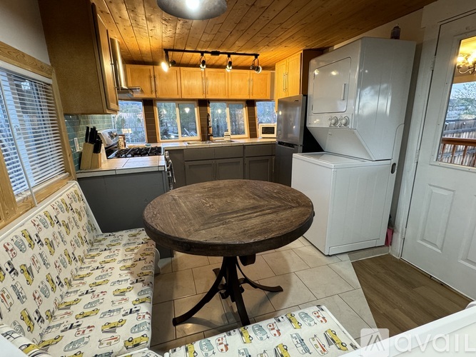 A kitchen with a table and chairs in the foreground and a refrigerator in the background.