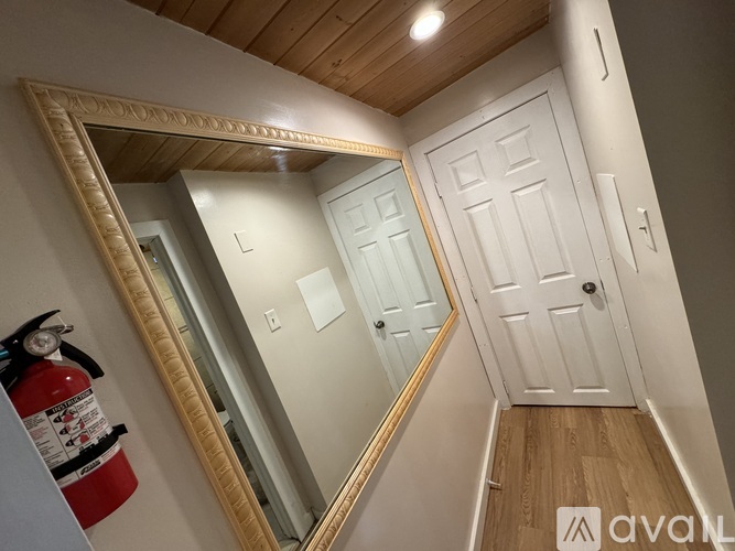 A hallway with a mirror on the wall and a fire extinguisher on the left.