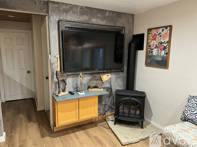 A living room with a fireplace and a television mounted on the wall.