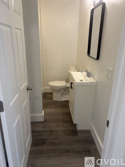 A bathroom with a toilet, sink and mirror.
