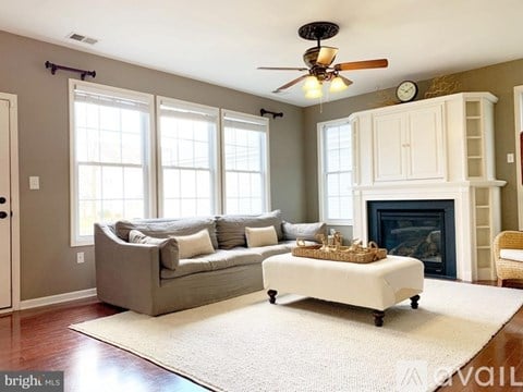 A living room with a grey couch and a white ottoman.