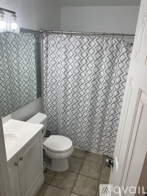 A bathroom with a toilet, sink, and shower curtain.