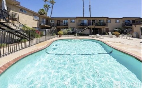 A swimming pool in front of a building with a black fence.