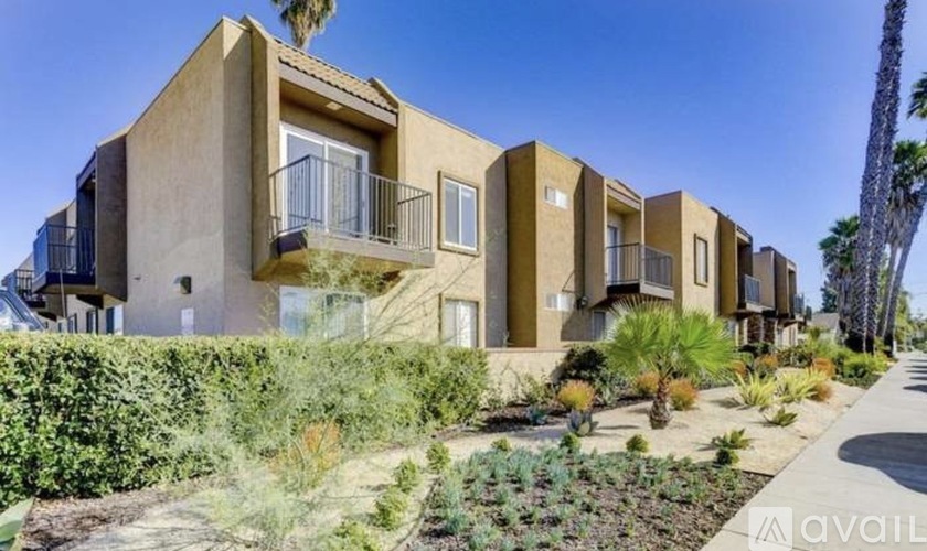 A row of modern houses with balconies and gardens in front.