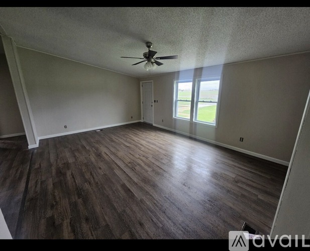 A room with a ceiling fan and wooden flooring.