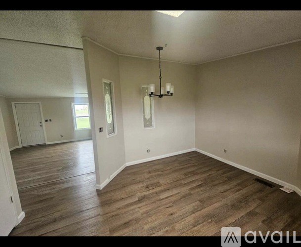 A room with wooden flooring and a chandelier.